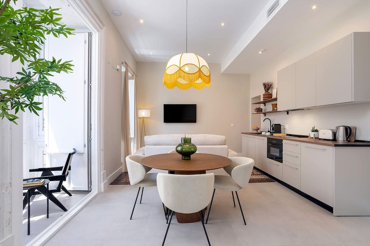 Une cuisine moderne avec un coin repas, une grande fenêtre et un luminaire suspendu.