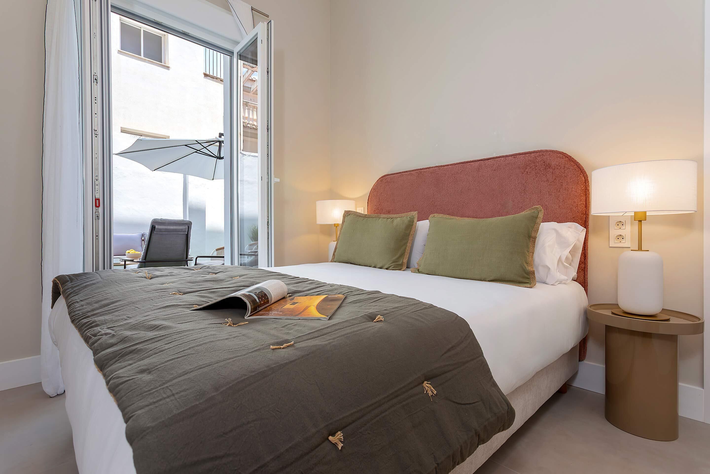 Habitación de hotel con cama, dos lámparas de noche, ventana y una silla.