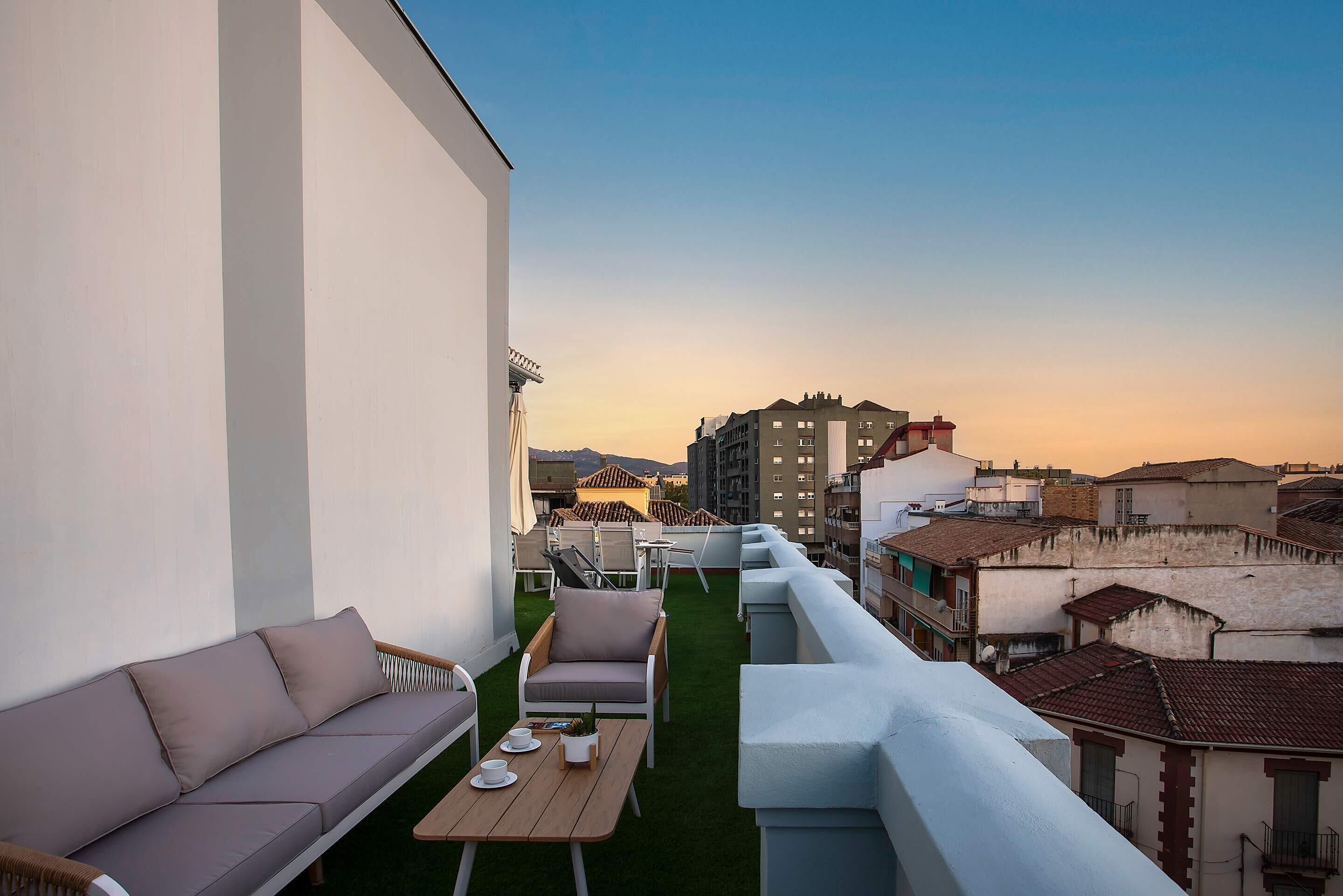 Une terrasse sur le toit, aménagée avec un canapé, des chaises et une table.
