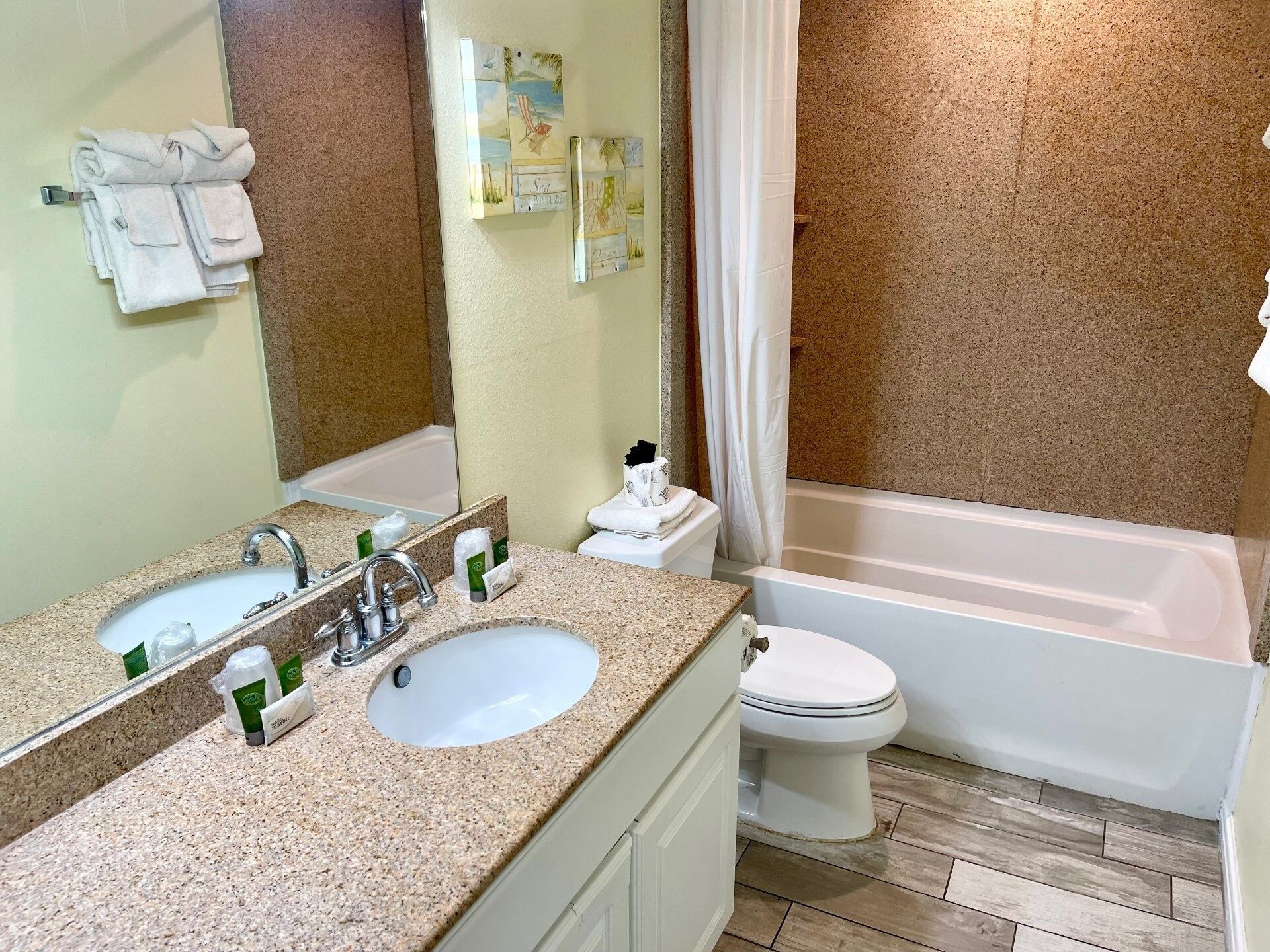 A bathroom with a sink, mirror, toilet, and bathtub.