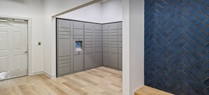 A hallway with a door, grey lockers, and a blue herringbone-patterned wall.