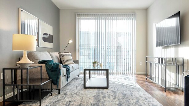 A modern living room with a sofa, coffee table, lamp, and TV. - Landing Apartments Humble near Bordersville (Humble)