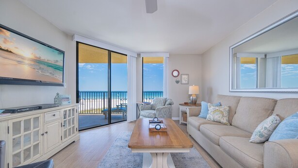 A living room with a wooden coffee table, beige sofa, and a large flat-screen TV. - Phoenix V 216 2 Bedroom Condo (Orange Beach)