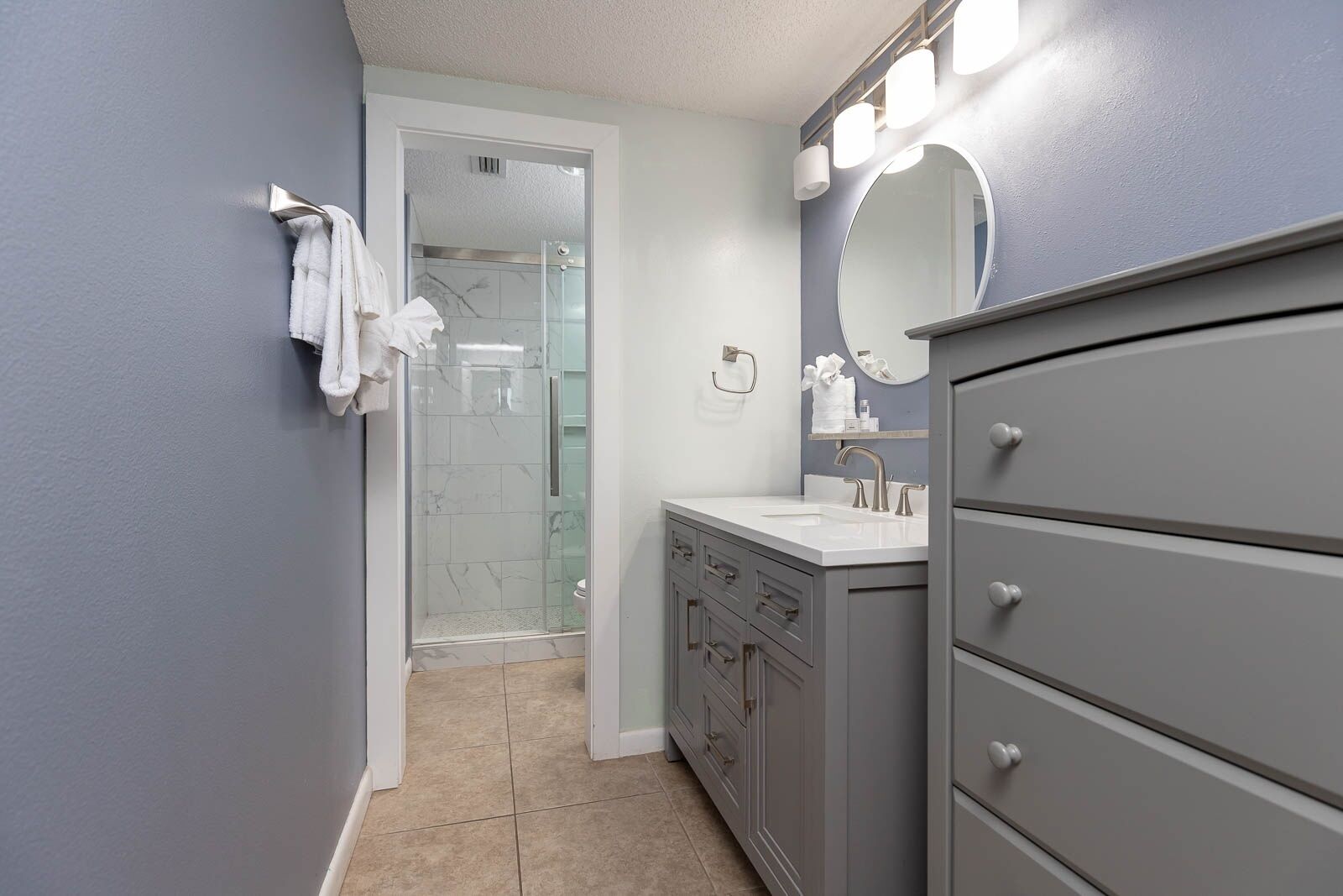 Une salle de bain avec une douche, un meuble-lavabo avec un miroir et un porte-serviettes.
