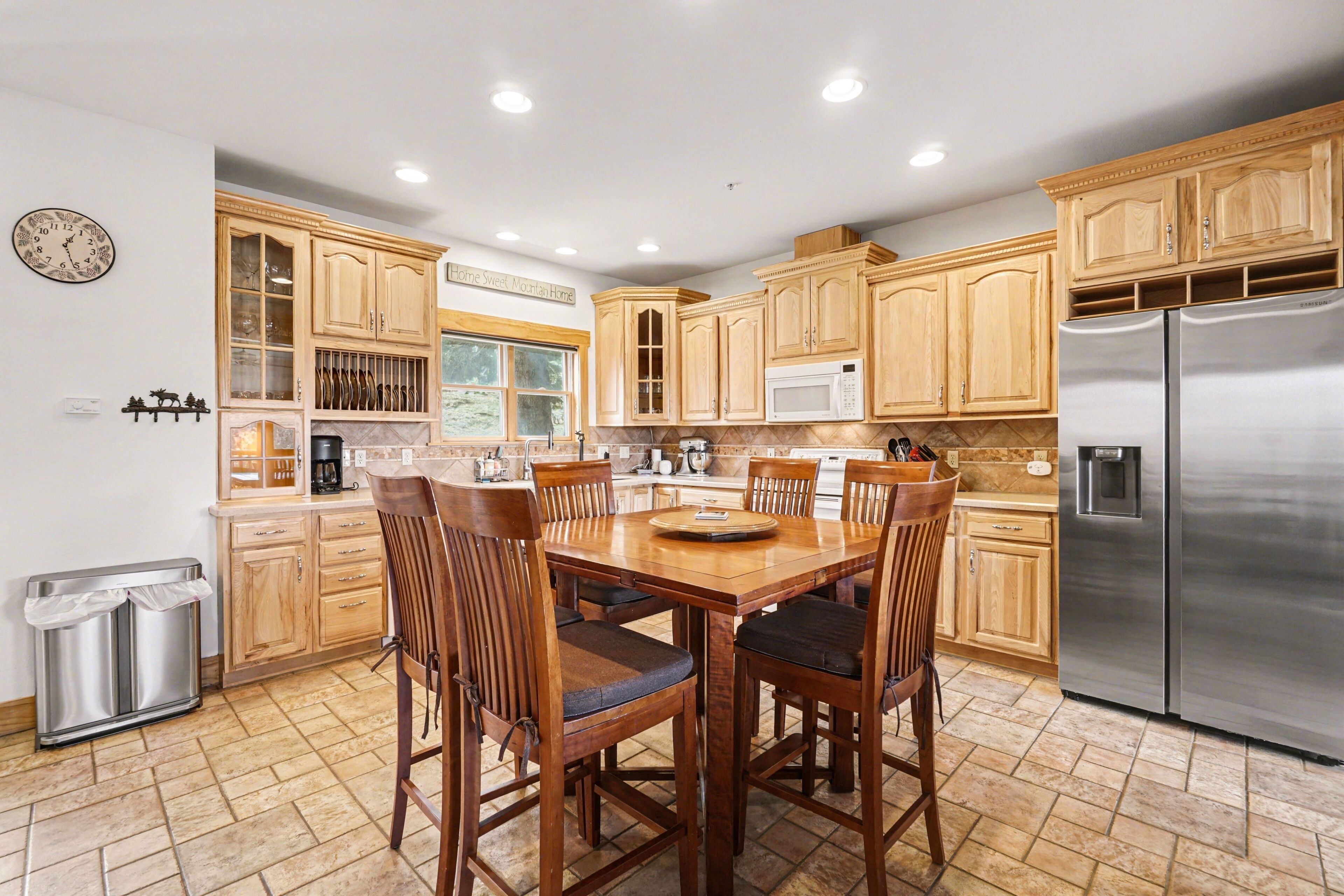 A kitchen with wooden cabinets, a stainless steel refrigerator, and a dining table with chairs.