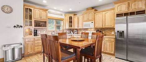 A kitchen with wooden cabinets, a stainless steel refrigerator, and a dining table with chairs.