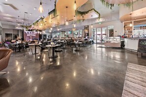 A spacious restaurant with multiple tables and chairs, hanging lights, and a counter with a menu. - Gulfview Retreat At The Palms 2 Bedroom Condo (Destin)