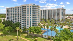 A multi-story hotel with balconies, a swimming pool, and surrounding greenery. - Gulfview Retreat At The Palms 2 Bedroom Condo (Destin)