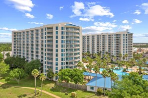 A multi-story hotel with balconies, a swimming pool, and surrounding greenery. - Gulfview Retreat At The Palms 2 Bedroom Condo (Destin)