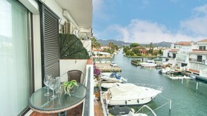 A balcony with a table and chairs, overlooking a marina with boats docked. - WELCS STUDIO 301 EMP with view of the canal (Empuriabrava)