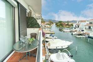 Un balcone con tavolo e sedie, affacciato su una marina con imbarcazioni ormeggiate.