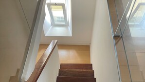 Eine Holztreppe mit Glastrennwand, die zu einem Raum mit Oberlichter führt.