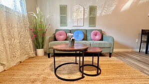 Un salon comprenant un canapé, deux tables rondes, une plante en pot et un mur agrémenté de volets décoratifs.
