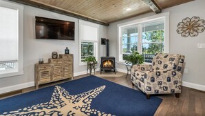 Ein Wohnzimmer mit Kamin, einer Couch, einem Fernseher und einem großen Fenster.