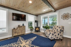 A living room with a fireplace, a sofa, a TV, and a large window. - Newly built 2018. Single family home with views and 5 minute walk to beach. (Hampton)