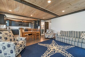 A modern interior with a wooden ceiling, a dining area with a wooden table and chairs, a striped sofa, and a star-patterned rug. - Newly built 2018. Single family home with views and 5 minute walk to beach. (Hampton)