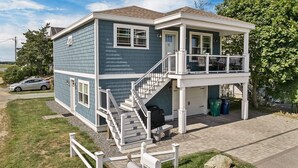 Ein zweistöckiges Haus mit überdachter Veranda, einer Treppe und einer Garage.