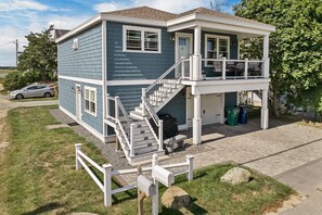 A two-story house with a covered porch, a staircase, and a garage. - Newly built 2018. Single family home with views and 5 minute walk to beach. (Hampton)