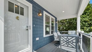 Eine überdachte Veranda mit Tisch und Stühlen, eine weiße Tür und eine blaue Außenwand.