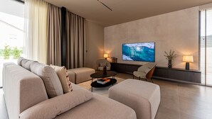 A modern living room with a sofa, armchairs, a coffee table, and a TV on the wall. - Villa Carrara ZadarVillas (Pakoštane)
