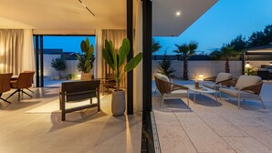 A modern living room with a large window, a sofa set, a coffee table, and a potted plant. - Villa Carrara ZadarVillas (Pakoštane)