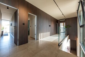 Ein modernes Interieur mit einer Holzwand, einem Glasgeländer und einer Treppe.