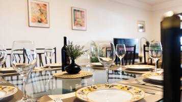 A dining table set with plates, glasses, and cutlery, with a bottle and a small plant on the table.