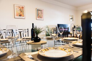 A dining table set with plates, glasses, and cutlery, with a bottle and a small plant on the table. - Casa de 4 quartos com AC no Ipiranga (São Paulo)