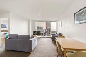 Una sala de estar moderna con un sofá, un televisor y una mesa de comedor.