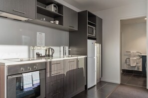 A modern kitchen with a built-in oven, a kettle, and a refrigerator. - 19th Floor 1BDR Apartment Steps from SkyCity (Auckland)