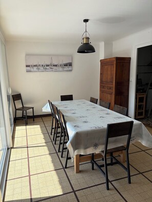 A dining area with a table set for six, chairs, a wooden cabinet, and a ceiling fan.