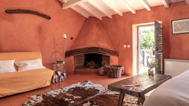Um quarto aconchegante com lareira, um sofá, uma mesa de jantar e um tapete de couro de vaca.