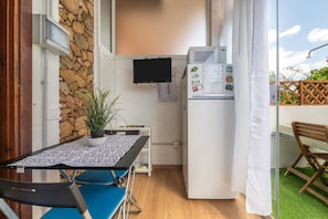 A small kitchen with a refrigerator, a potted plant, and a table with chairs. - Holiday Home 'Casa Clà 2' with Private Terrace, Garden, and Air Conditioning (Crabonaxa)