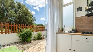 Eine Küche mit Holzarbeitsplatte, einem Fenster und Blick auf einen Garten mit Holzzaun.