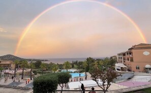 A resort with a pool, palm trees, and a view of the sea. - Beautiful renovated apartment with panoramic sea view at Cap Esterel (Saint-Raphaël)
