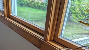 A window with wooden frames and a view of a grassy yard. - Cozy 3-bedroom townhome w/ AC in pleasant Paramus. World Cup, negotiable rates (Paramus)