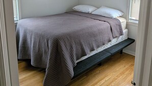 A bedroom with a bed, a bench, and a ceiling light. - Cozy 3-bedroom townhome w/ AC in pleasant Paramus. World Cup, negotiable rates (Paramus)