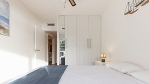 Une chambre à coucher avec un lit, une table de chevet avec une lampe, une armoire et un tableau au mur.