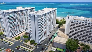 Een hoog hotel met meerdere verdiepingen, een parkeerplaats en uitzicht op de oceaan.