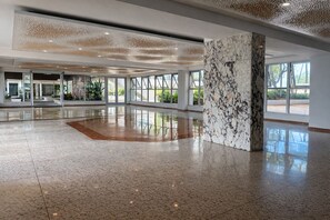 A spacious lobby with a polished floor, large windows, and a marble column. - Beachside at Isla Verde (Carolina)