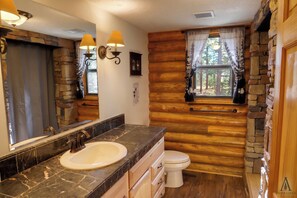Une salle de bain avec un mur en pierre, un lambris en bois, un lavabo et des toilettes.