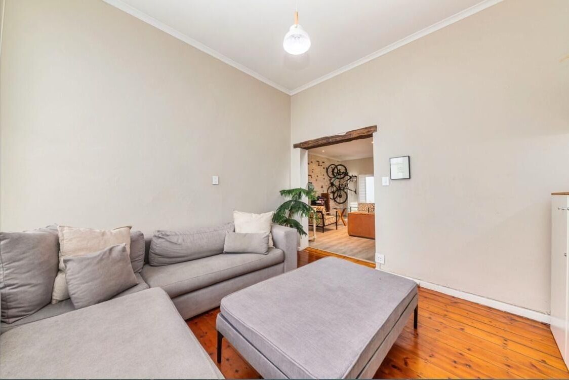 Ein Wohnzimmer mit grauem Sofa, grauem Hocker und Holzboden.