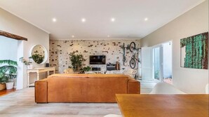 A modern living room with a large sofa, a dining table, and a TV. - 3 Bedroom Home in Gardens Cape Town (Cape Town)