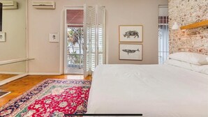 A bedroom with a bed, a patterned rug, a wall with a brick texture, and a door leading to an outdoor area. - 3 Bedroom Home in Gardens Cape Town (Cape Town)
