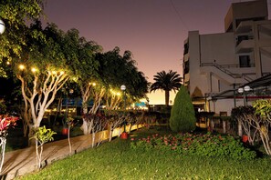 A landscaped garden with trees, a pathway, and a building with balconies.