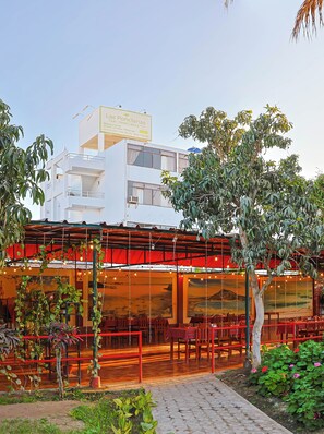 A building with a restaurant on the ground floor, featuring outdoor seating and a view of the surrounding area.