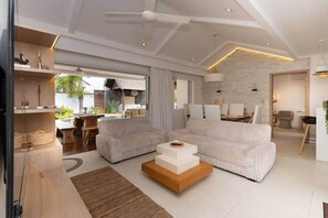 Ein modernes Wohnzimmer mit Sofa, Couchtisch und einem Essbereich mit Stühlen.