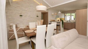 A modern dining area with a wooden table, white chairs, and pendant lighting. - Stunning Latanier villa-private pool in Grand Bay (Rivière du Rempart District)