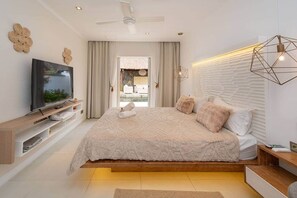 Ein modernes Schlafzimmer mit einem großen Bett, einem Fernseher auf einer Holzkonsole und Blick auf einen Außenpool.