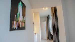 A hallway with a painting of a cityscape, a door, and a curtain. - Cube Apartments by Wiener Stadthalle (Vienna)